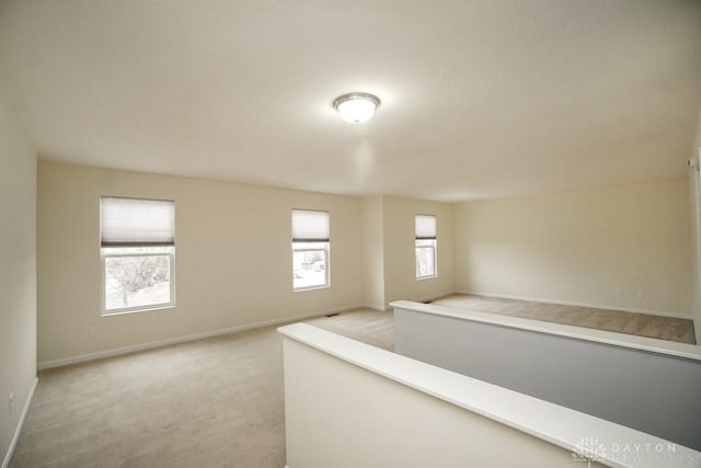 hall with baseboards and light colored carpet