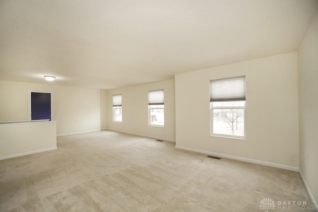 unfurnished room with light colored carpet, visible vents, and baseboards