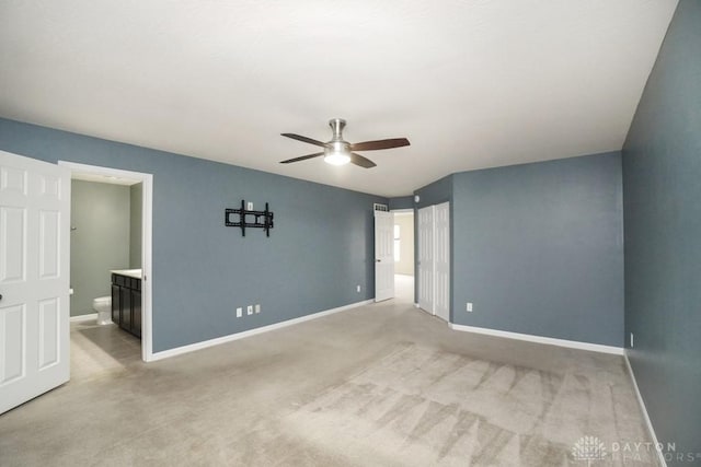 unfurnished bedroom featuring ensuite bath, baseboards, ceiling fan, and light colored carpet