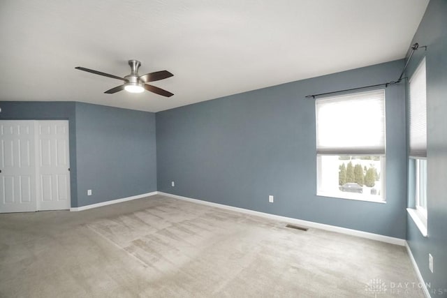 carpeted empty room featuring visible vents, baseboards, and ceiling fan