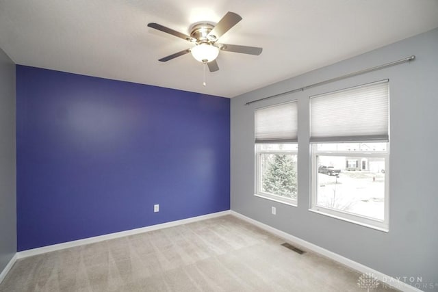 unfurnished room featuring a ceiling fan, baseboards, visible vents, and carpet flooring