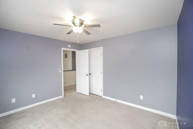 carpeted empty room featuring ceiling fan and baseboards