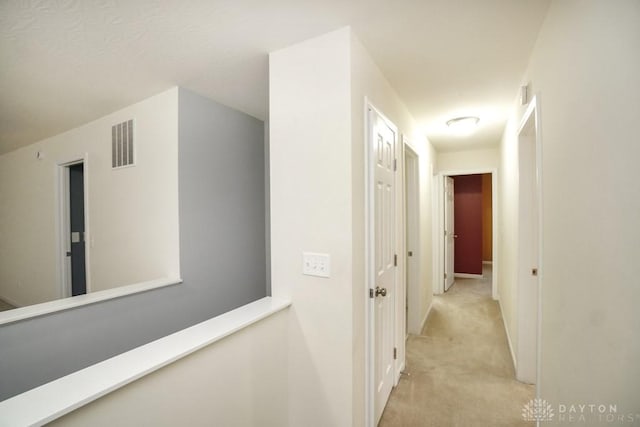 corridor with light carpet, an upstairs landing, and visible vents