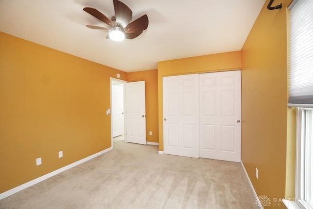 unfurnished bedroom featuring light carpet, a ceiling fan, baseboards, and a closet