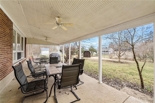 view of patio / terrace featuring a ceiling fan, an outbuilding, outdoor dining area, and a storage shed