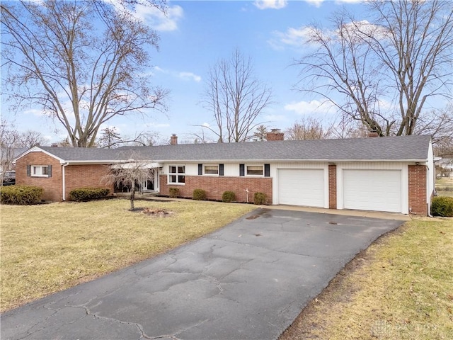 ranch-style house with aphalt driveway, an attached garage, brick siding, a chimney, and a front yard