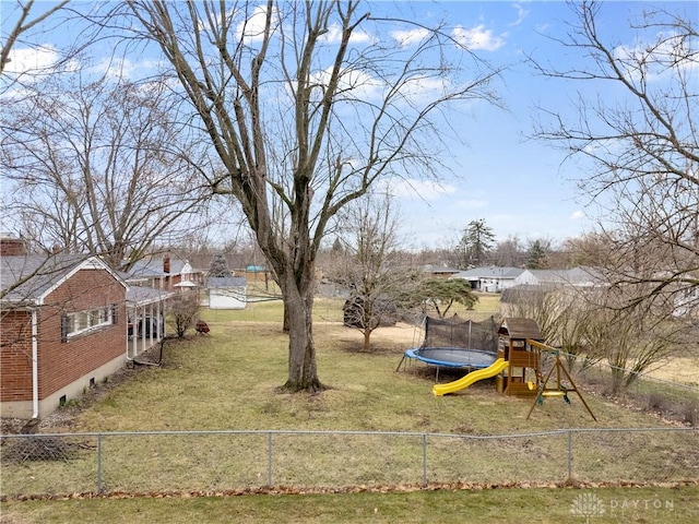 view of yard featuring a trampoline, a playground, and fence private yard