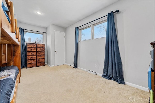 bedroom with light carpet, a baseboard heating unit, multiple windows, and baseboards