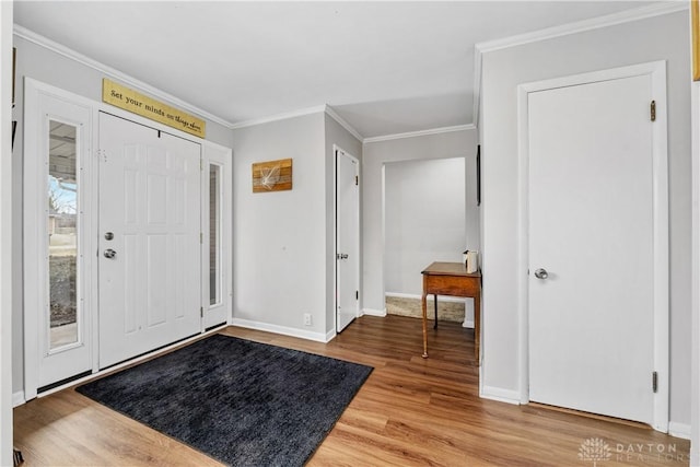 foyer featuring baseboards, ornamental molding, and wood finished floors