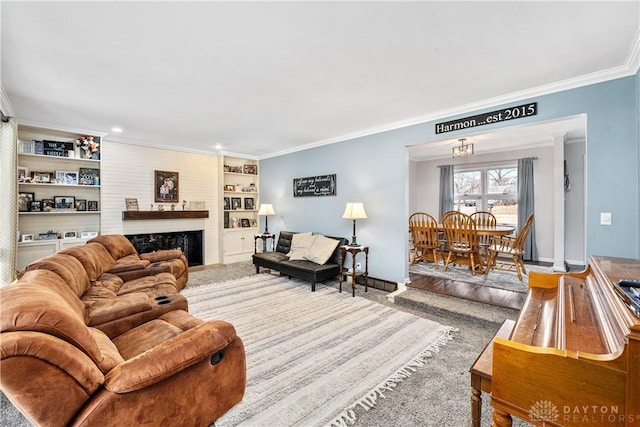 living area with built in features, a fireplace, crown molding, wood finished floors, and baseboards