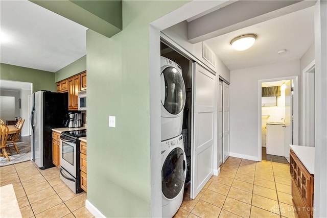 laundry area with stacked washing maching and dryer, laundry area, visible vents, and light tile patterned flooring