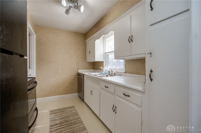 kitchen with stainless steel appliances, a sink, white cabinetry, baseboards, and light countertops