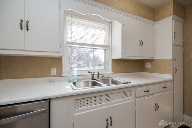 kitchen with backsplash, light countertops, stainless steel dishwasher, white cabinetry, and a sink