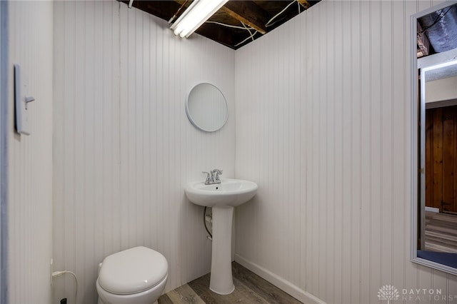 half bath featuring a sink, wood finished floors, and toilet