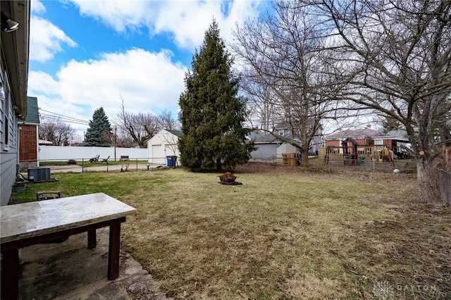 view of yard featuring an outdoor fire pit, a fenced backyard, an outdoor structure, and central air condition unit