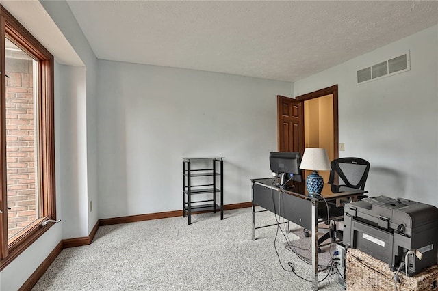 carpeted office with visible vents, a textured ceiling, and baseboards