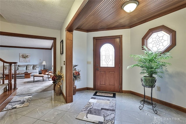 entrance foyer with stairs, baseboards, a textured ceiling, and ornamental molding