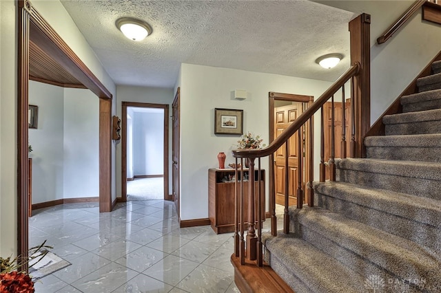 interior space with a textured ceiling, baseboards, and stairs