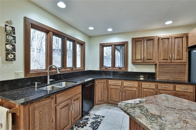 kitchen featuring brown cabinetry, black dishwasher, light tile patterned flooring, and a sink