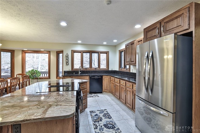 kitchen featuring a sink, black appliances, a kitchen island, and a wealth of natural light