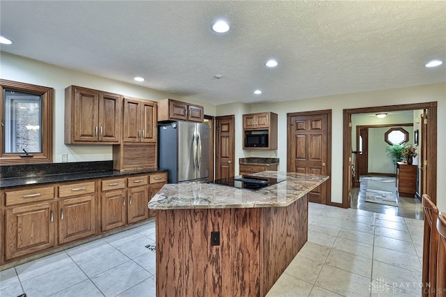 kitchen featuring a center island, recessed lighting, light tile patterned flooring, dark stone counters, and black appliances