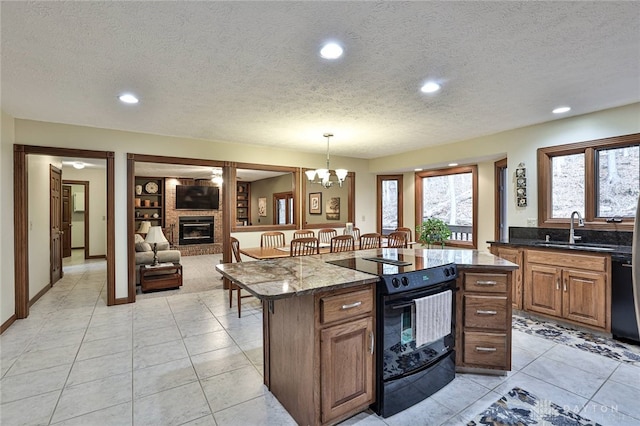 kitchen with a fireplace, a kitchen island, a sink, a textured ceiling, and black appliances