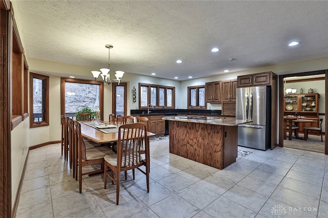 kitchen with light tile patterned floors, a kitchen island, a chandelier, and freestanding refrigerator