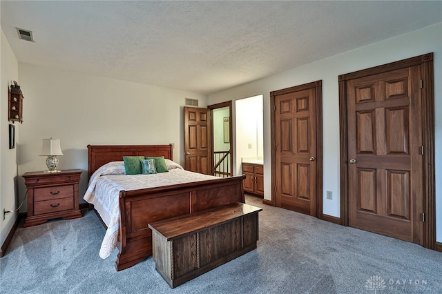 carpeted bedroom with a textured ceiling, ensuite bathroom, visible vents, and baseboards