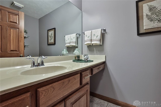 bathroom featuring a textured ceiling, visible vents, vanity, baseboards, and tile patterned floors