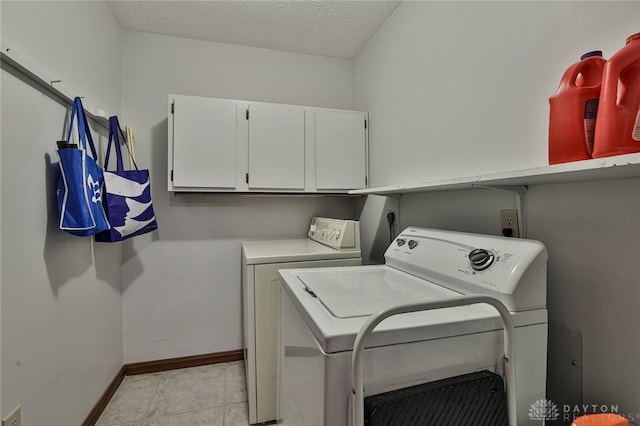 laundry room with light tile patterned floors, cabinet space, a textured ceiling, washer and dryer, and baseboards