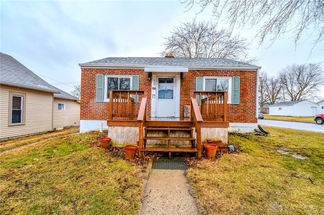 bungalow with a front lawn and brick siding