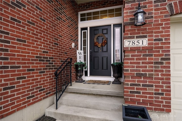 property entrance with a garage and brick siding