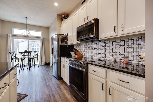 kitchen with white cabinetry, appliances with stainless steel finishes, dark wood-style floors, tasteful backsplash, and pendant lighting