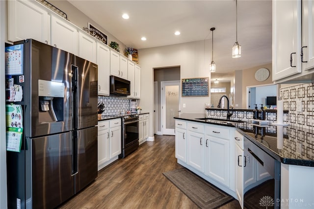 kitchen with dark countertops, dark wood-style flooring, a sink, stainless steel appliances, and backsplash