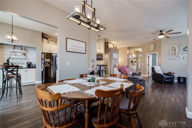 dining room with dark wood-style floors, ceiling fan with notable chandelier, and baseboards