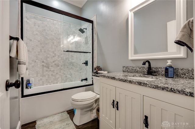 bathroom with enclosed tub / shower combo, vanity, toilet, and wood finished floors