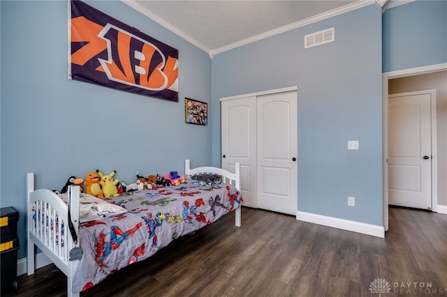 bedroom featuring baseboards, visible vents, ornamental molding, wood finished floors, and a closet