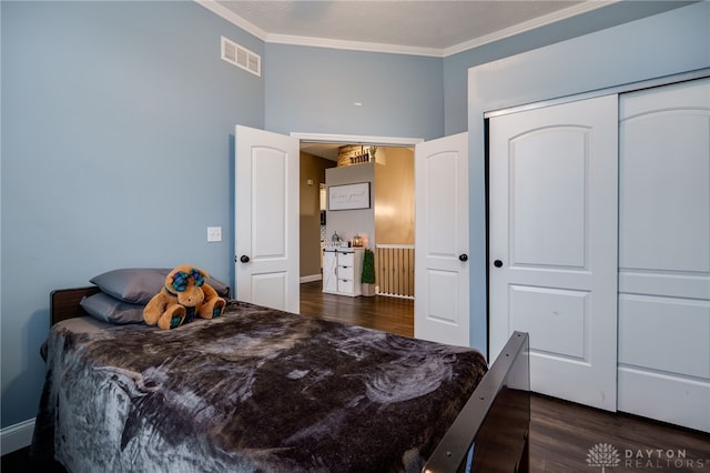 bedroom with ornamental molding, a closet, dark wood finished floors, and visible vents