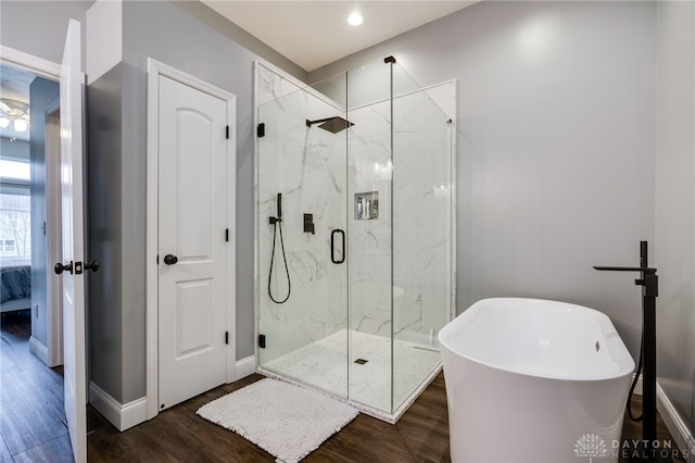 full bathroom featuring a freestanding tub, connected bathroom, wood finished floors, baseboards, and a marble finish shower