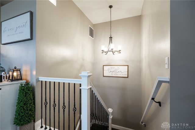 stairs with an inviting chandelier, baseboards, and visible vents