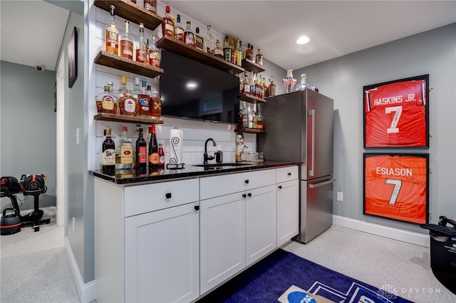 bar featuring baseboards, freestanding refrigerator, a sink, indoor wet bar, and recessed lighting