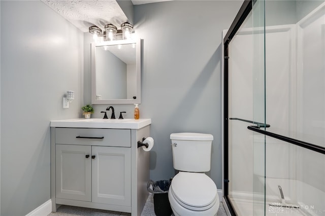 bathroom with toilet, vanity, and a shower with shower door