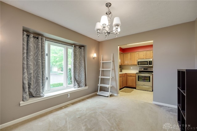 kitchen featuring light colored carpet, baseboards, appliances with stainless steel finishes, decorative light fixtures, and an inviting chandelier