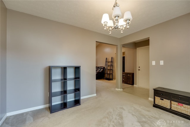 hall with carpet flooring, a textured ceiling, baseboards, and an inviting chandelier