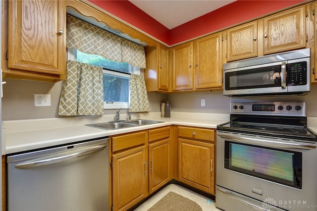 kitchen featuring brown cabinets, appliances with stainless steel finishes, light countertops, and a sink