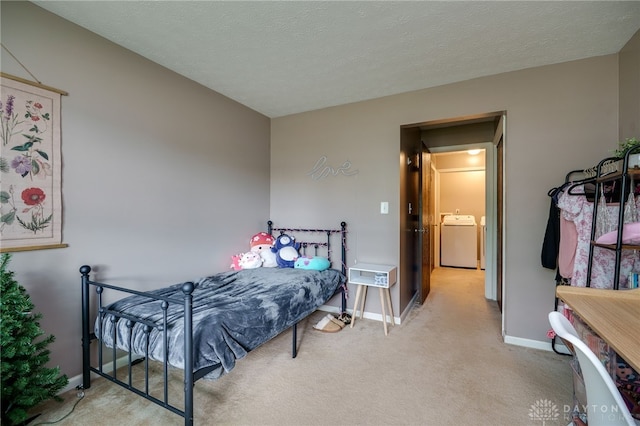 bedroom featuring carpet, washing machine and dryer, a textured ceiling, and baseboards