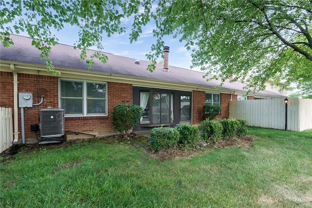 rear view of property with a yard, fence, cooling unit, and brick siding