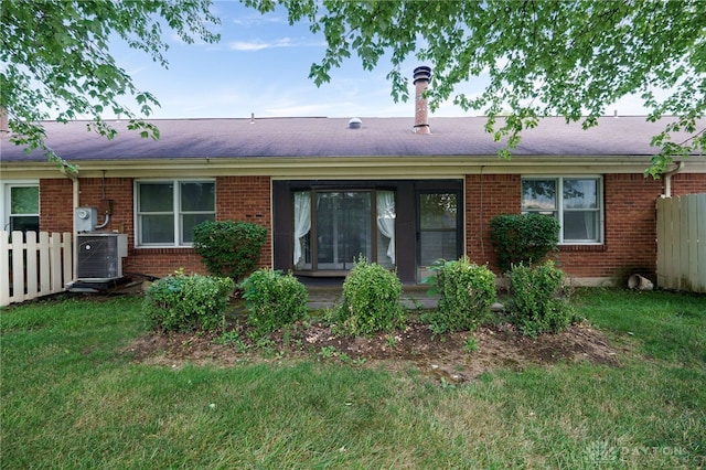 back of house with fence, a lawn, cooling unit, and brick siding