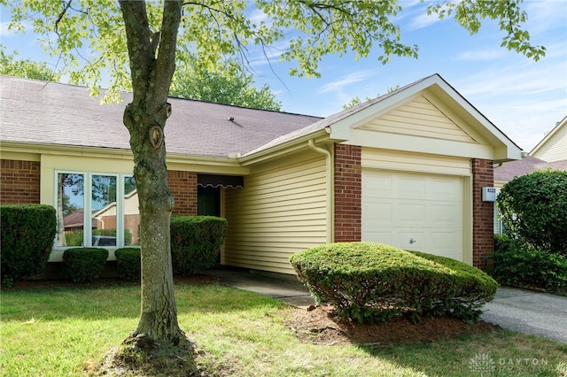 ranch-style home featuring an attached garage, roof with shingles, a front yard, and brick siding