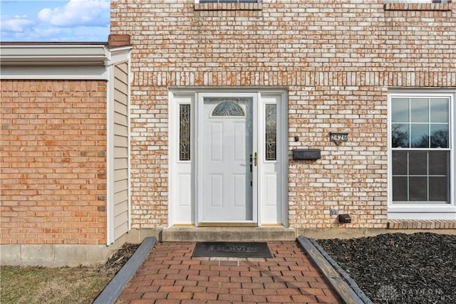 view of exterior entry featuring brick siding